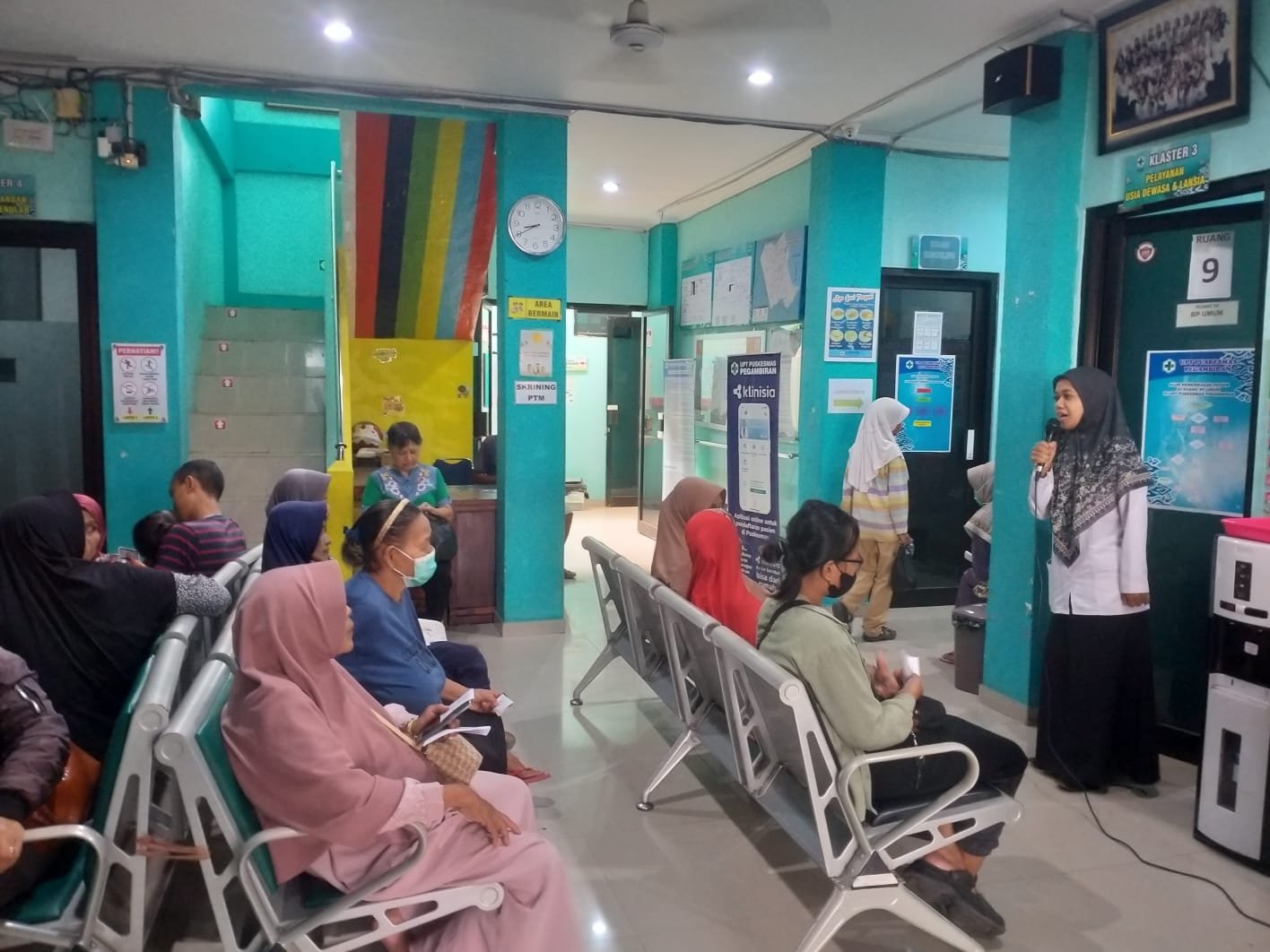 KEGIATAN PENYULUHAN DALAM GEDUNG TENTANG MOBILE JKN KEPADA PASIEN DI RUANG TUNGGU PUSKESMAS PEGAMBIRAN OLEH PETUGAS REKAM MEDIS